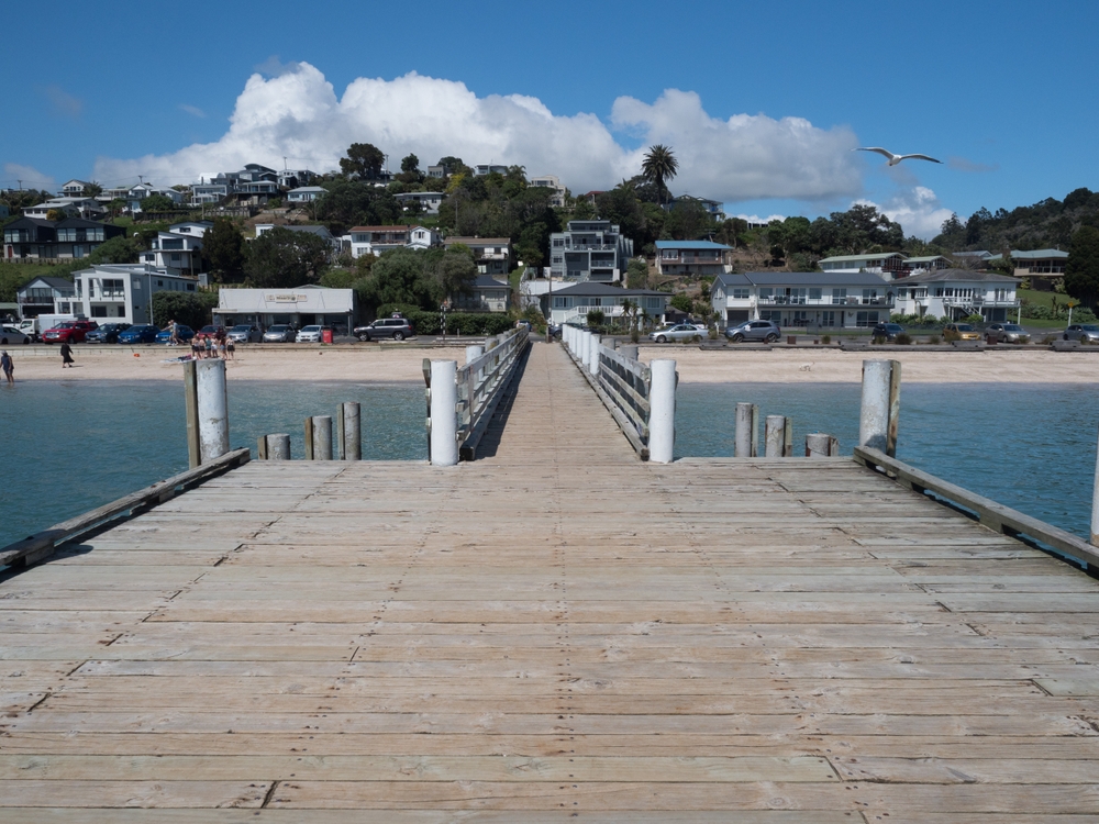 Maraetai-Auckland-New Zealand- 01 November,2022: View from the end of the Maraetai Pier wharf looking back at coastal housing and beach. New Zealand.